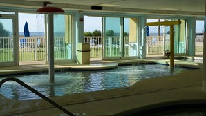 An indoor swimming pool with clear views of the outside, a water fountain, and a covered seating area.