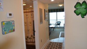 A hallway with a welcome sign, a thermostat, and a 'House Rules' sign.