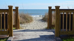 A wooden boardwalk leading to the beach with a clear view of the ocean.