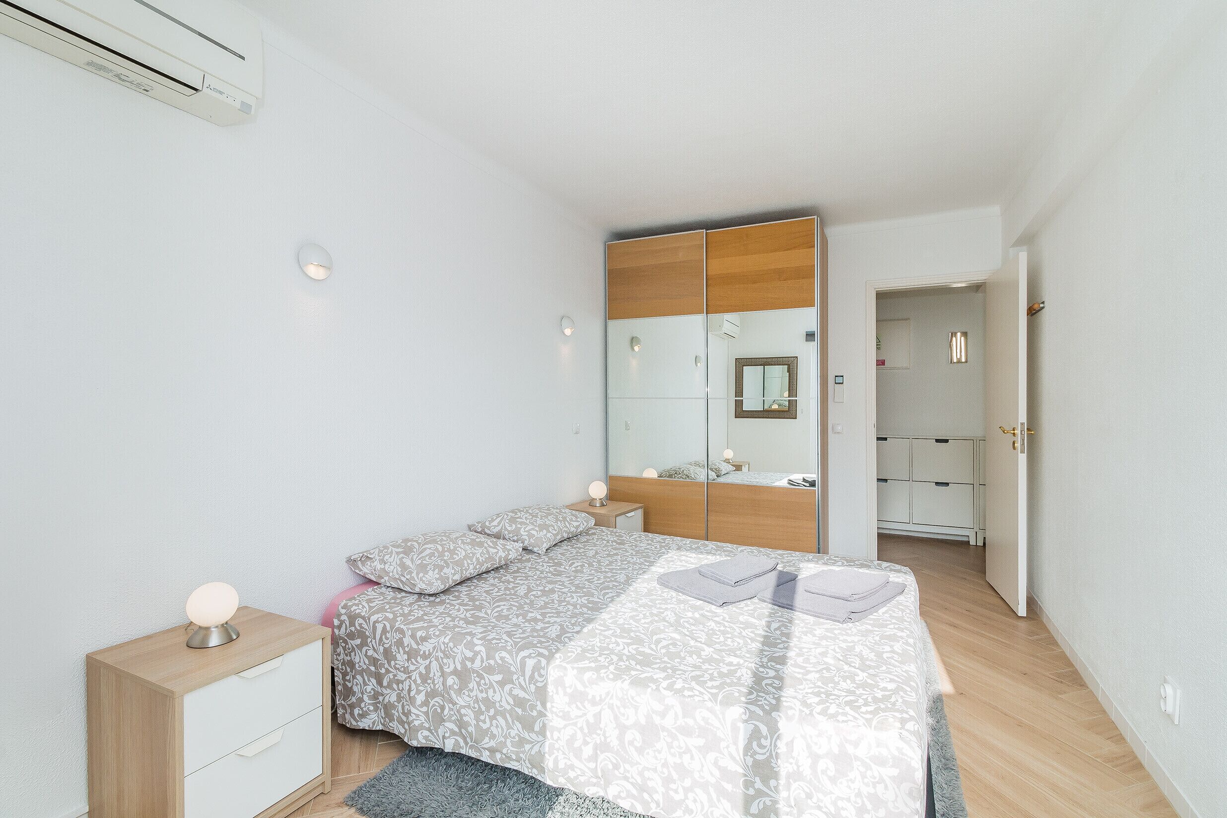 A bedroom with a bed, bedside table, nightstand, and a wardrobe.