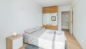 Ein Schlafzimmer mit Bett, Nachttisch, Beistelltisch und Kleiderschrank.