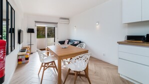Eine moderne Küche mit weißen Schränken, einem Holztisch und weißen Stühlen.