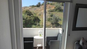 Ein Balkon mit Tisch, Stühlen und Blick auf eine hügelige Landschaft.