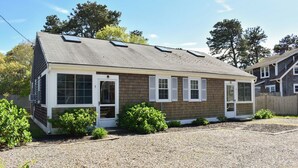 A single-story house with a sloped roof, white-framed windows, and a gravel driveway.