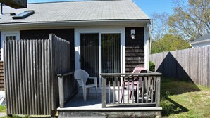 A small house with a wooden deck, a sliding glass door, and a porch with outdoor furniture.