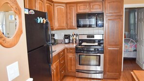 A kitchen with wooden cabinets, a stainless steel refrigerator, a microwave, a stove, and an oven.