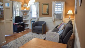A living room with a sofa, armchair, TV, and a small table.