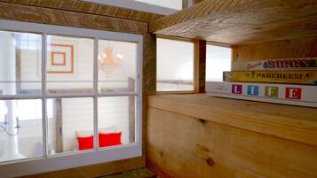 Cozy retreat with a wooden shelf and bench, featuring a collection of books and a window with a geometric pattern reflection.