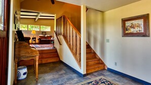 A spacious living area with a wooden staircase, a piano, and a rug.