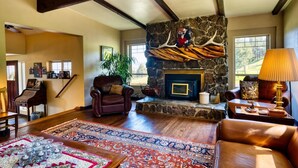A cozy living room with a stone fireplace, leather furniture, and a piano.