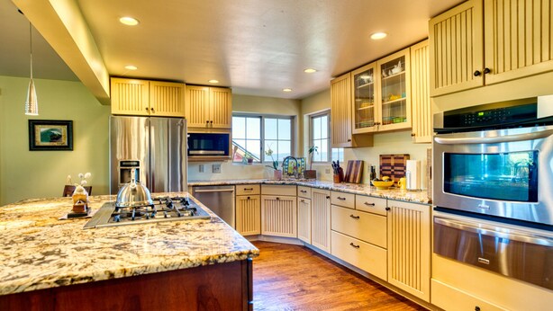A spacious kitchen with a large island, stainless steel appliances, and wooden cabinets.