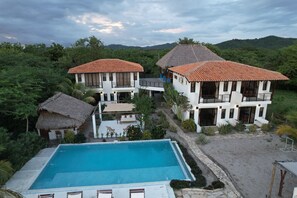 A resort with two-story buildings, a swimming pool, and a thatched-roof structure. - Costa Oeste (Popoyo)