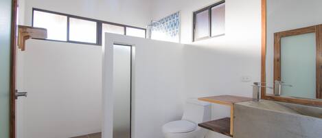 Un baño moderno con ducha, inodoro y tocador.