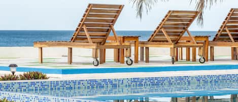 A poolside area with wooden lounge chairs and a tiled pool.