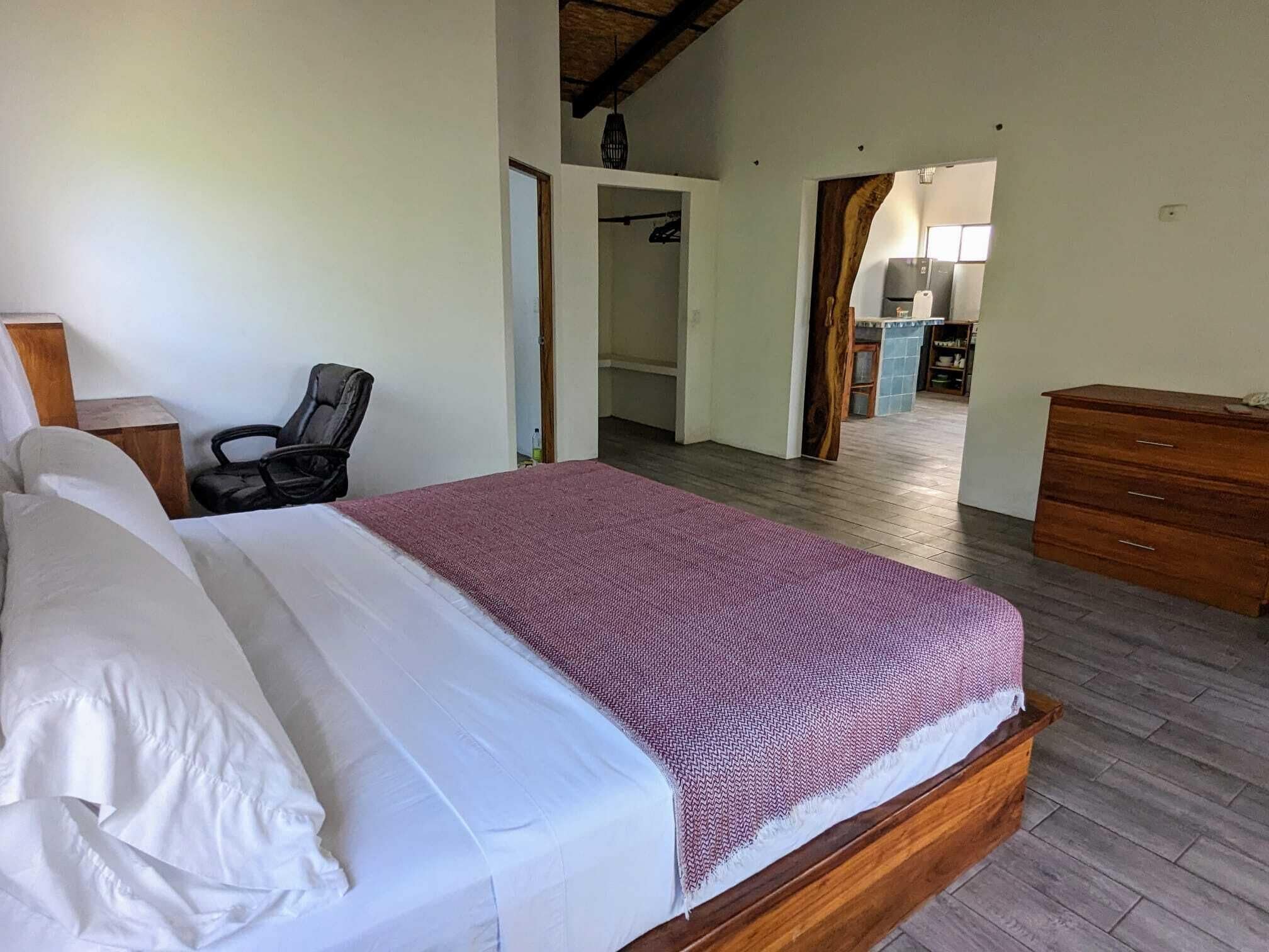 A bedroom with a wooden bed, a chair, and a wooden dresser.