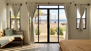A room with a bed, a sofa, and a large sliding glass door leading to a beach view. - Costa Oeste (Popoyo)