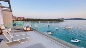 Un balcón con sillones de descanso con vistas a un puerto deportivo con barcos.