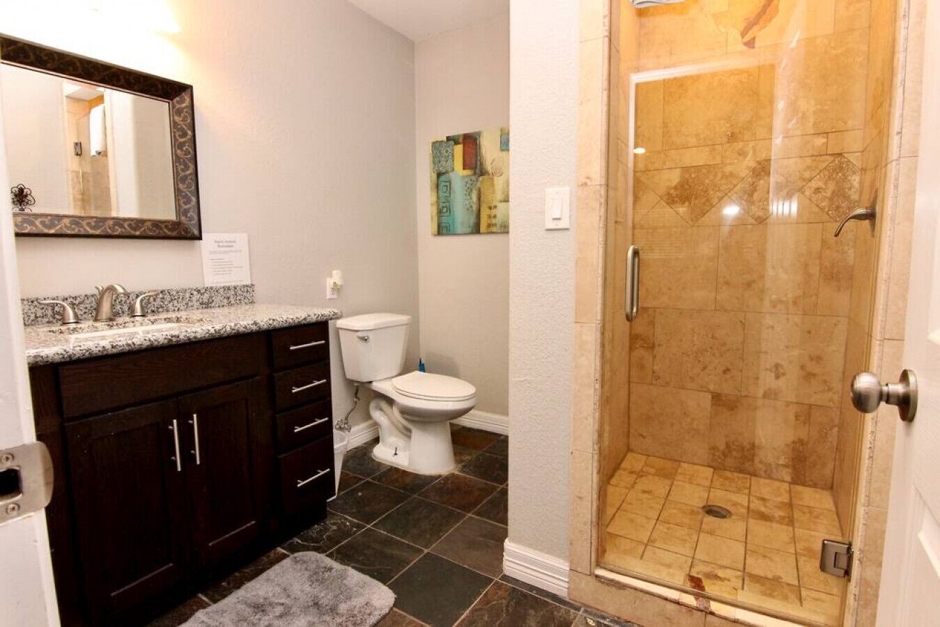 A bathroom with a shower, toilet, and vanity.