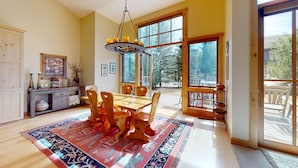 A dining area with a wooden table and chairs, a rug, and a hanging light fixture. - Angani Way Townhome 102 -Beautiful Space! Tesla Charger in the Garage (Elkhorn)