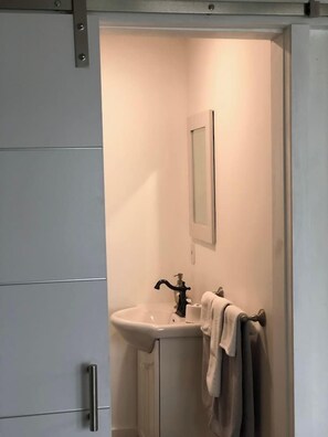 Un bagno con un lavandino, uno specchio e un asciugamano su un portasciugamani.