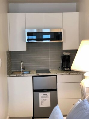 A compact kitchen with a built-in microwave, a coffee maker, and a refrigerator. - Beachfront duplex Cottage (Qualicum Beach)