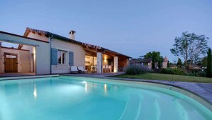 Et moderne hus med swimmingpool, overdækket terrasse og velplejet have.