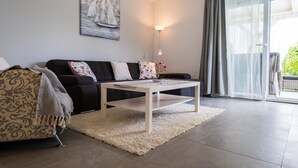 Een moderne woonkamer met een bank, een salontafel en een schilderij aan de muur.