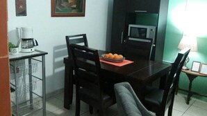 Un comedor con una mesa, sillas, microondas, cafetera y un cuadro en la pared.
