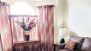 Un salon comprenant un canapé, une table basse et un vase décoratif avec des fleurs.