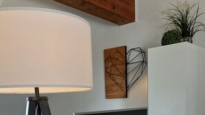 Ein modernes Wohnzimmer mit einem Flachbildfernseher auf einer weißen Unterhaltungseinheit, einer Lampe und einem Bett im Hintergrund.