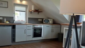 Eine moderne Küche mit Holzbalken, einem eingebauten Backofen, einer Mikrowelle und einer Dreibeinlampe.