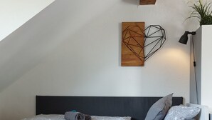 Ein modernes Schlafzimmer im Loft-Stil mit einer eingebauten Schlafcouch, einem kleinen runden Tisch und einer Stehlampe.