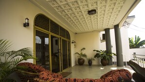 Eine überdachte Veranda mit Korbmöbeln, Blumentöpfen und einer dekorativen Decke.