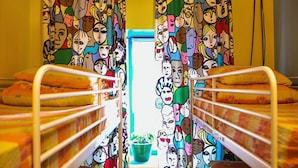 A room with bunk beds, colorful curtains with cartoon faces, and a small potted plant. - Funky Mamaliga Hostel (Chisinau)