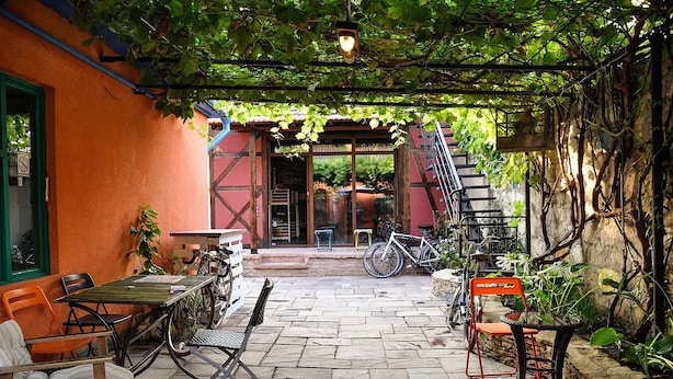 An outdoor patio with stone flooring, tables, chairs, and bicycles. - Funky Mamaliga Hostel (Chisinau)