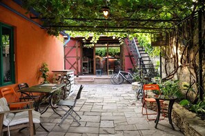 An outdoor patio with stone flooring, tables, chairs, and bicycles. - Funky Mamaliga Hostel (Chisinau)