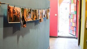 A hallway with a series of photographs on a wall, leading to a brightly colored room with a pink door and a tiled floor. - Funky Mamaliga Hostel (Chisinau)
