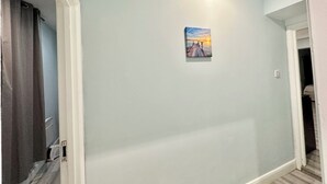 A hallway with a light blue wall, a small painting of a sunset, and a door leading to another room. - King’s Cross Apartment Ground floor  (London)