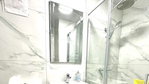 A bathroom with a toilet, sink, mirror, and glass-enclosed shower. - King’s Cross Apartment Ground floor  (London)