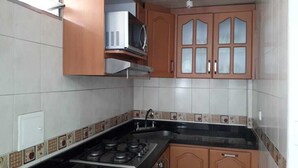 A kitchen with a gas stove, cabinets, and a microwave.