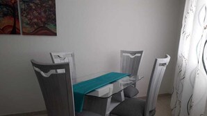 A dining area with a glass table, grey upholstered chairs, and a teal table runner.