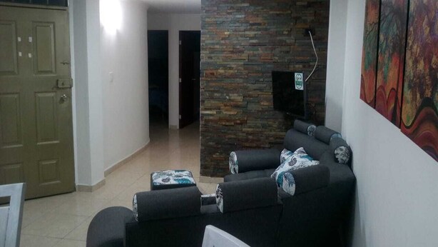 A living room with a stone accent wall, a sofa set, and a painting on the wall.