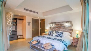 A bedroom with a bed, bedside tables, a bench, and a wardrobe. - BEACHFRONT & TERRACE CONDO! (Puerto Vallarta)