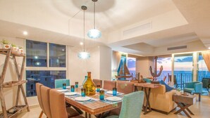 A dining area with a wooden table, chairs, and a view of the ocean. - BEACHFRONT & TERRACE CONDO! (Puerto Vallarta)