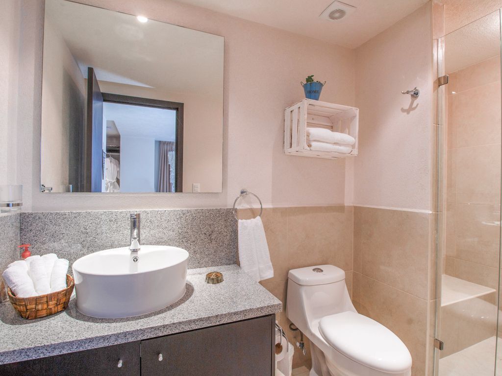 A bathroom with a large mirror, a sink, a toilet, and a shower area.