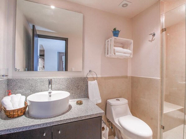 Een badkamer met een grote spiegel, een wastafel, een toilet en een douchehoek.