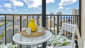A balcony with a wicker table, a yellow water jug, and a white mug. - 25th Floor Ocean Views! AC, Washer/Dryer, Wi-Fi, Rooftop Pool, FREE Parking! (Honolulu)