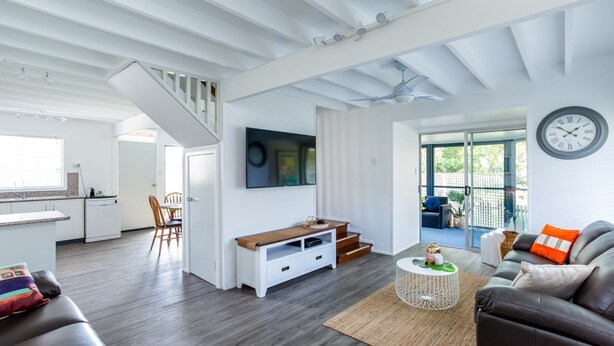 A modern living space with a staircase, a dining area, a kitchen, and a seating area with a view to the outside. - Wayfarers Beachouse - Rainbow Beach. Everything you need, just metres to the beach. Pets welcome (Rainbow Beach)