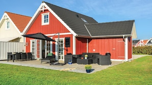 A red barn with a black roof, a patio with outdoor furniture, and a small garden area. - Beautiful home in Brenderup Fyn (Brenderup Fyn)