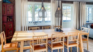Ein Essbereich mit einem Holztisch und Stühlen, zwei Pendelleuchten und einem roten Schrank mit Dekoration.
